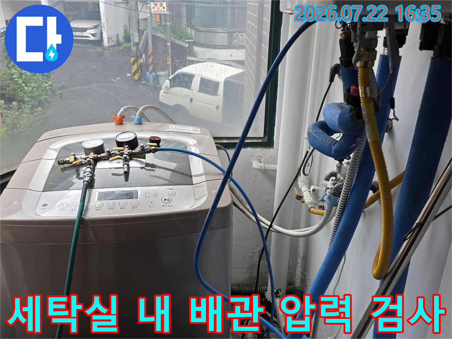 압력 게이지와 파란색 호스가 연결된 탐지 장비를 이용해 세탁실 수도 배관을 점검하는 장면