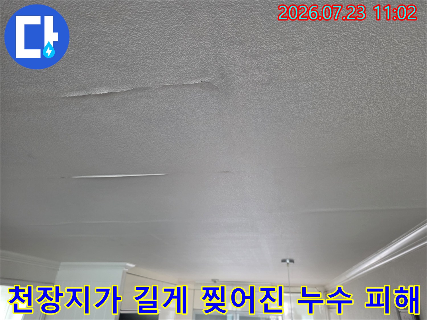 흰색 거실 천장의 마감재가 수분 유입으로 인해 가로 방향으로 갈라지고 들뜬 상태의 사진