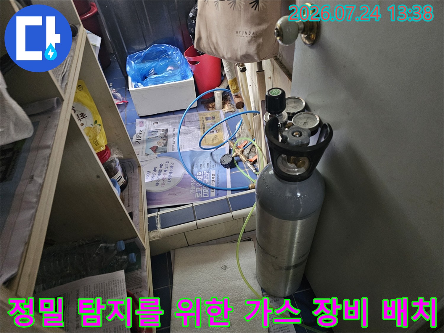 바닥에 놓인 회색 가스 탱크와 연결된 파란색 호스의 누수 탐지 세팅 모습