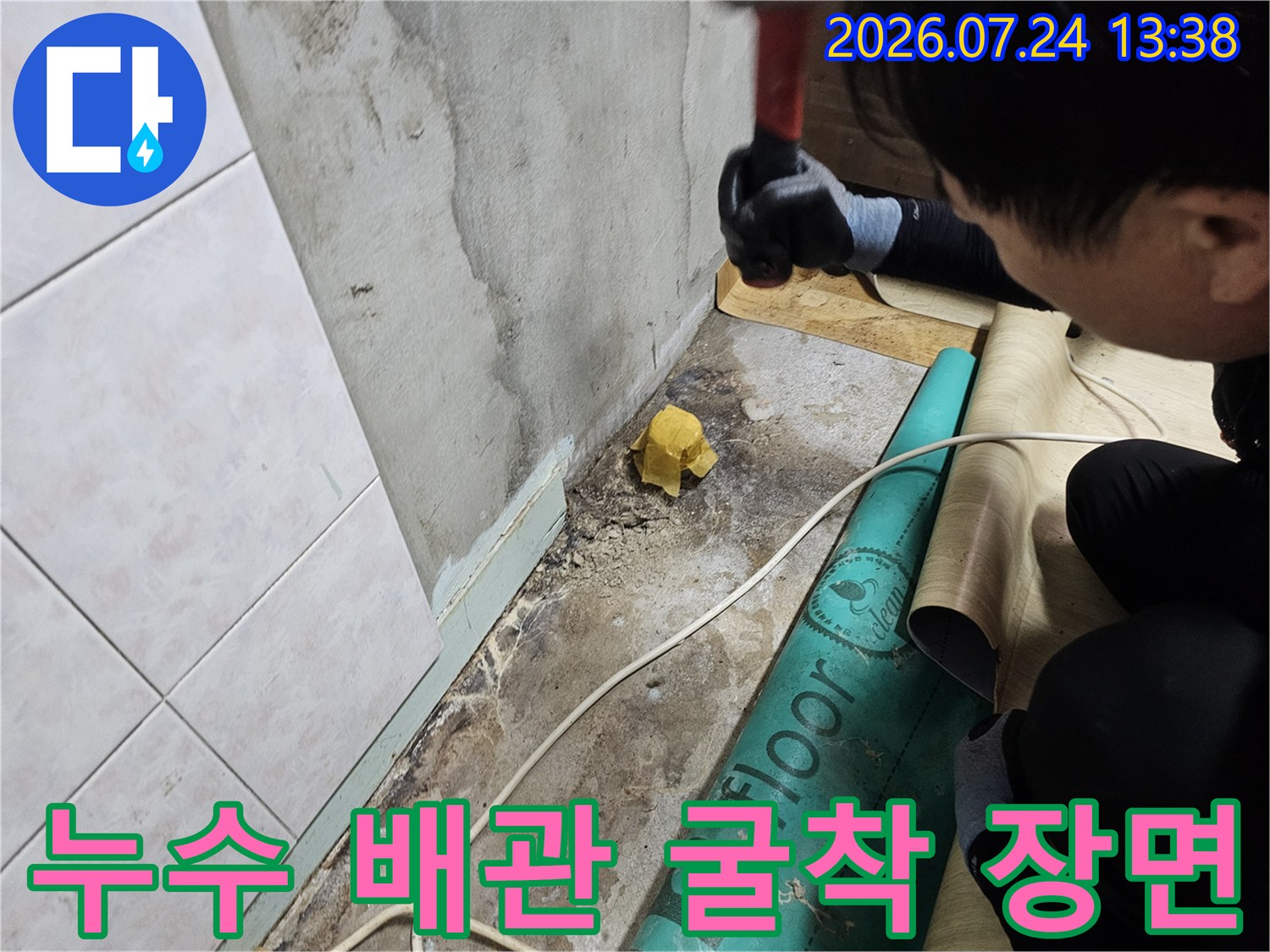 작업자가 바닥 보호재 위에서 함마드릴을 이용해 누수 지점을 파헤치는 모습