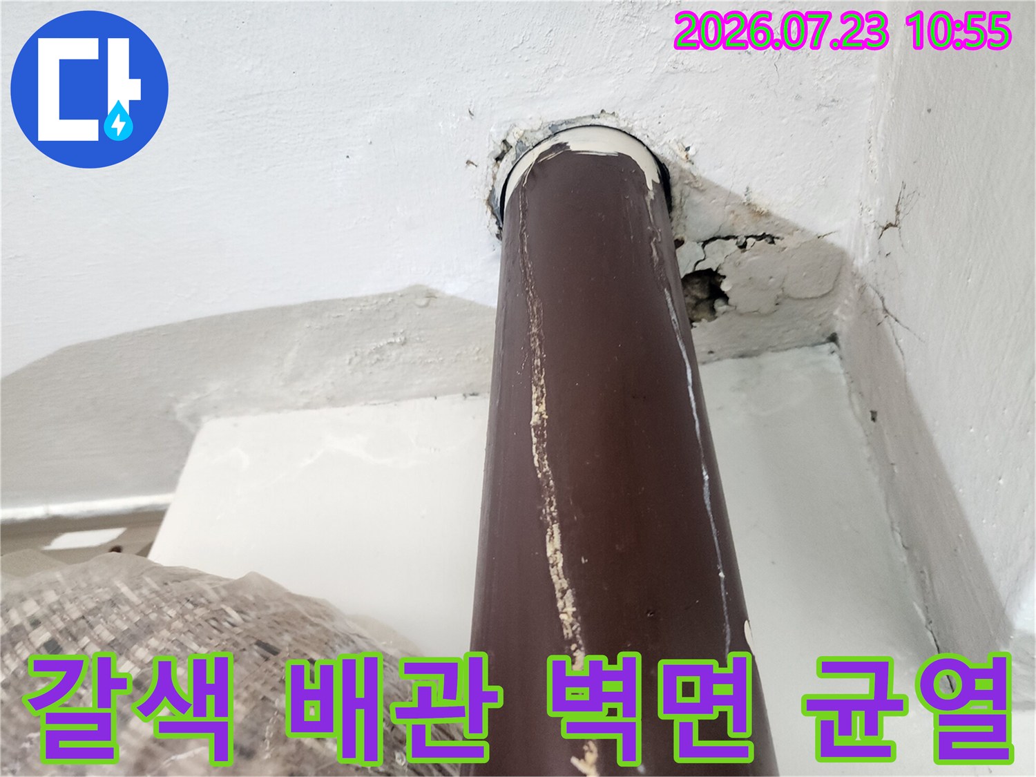 벽면에 고정되지 않고 틈이 생긴 갈색 플라스틱 배관과 주변의 시멘트 균열 상태