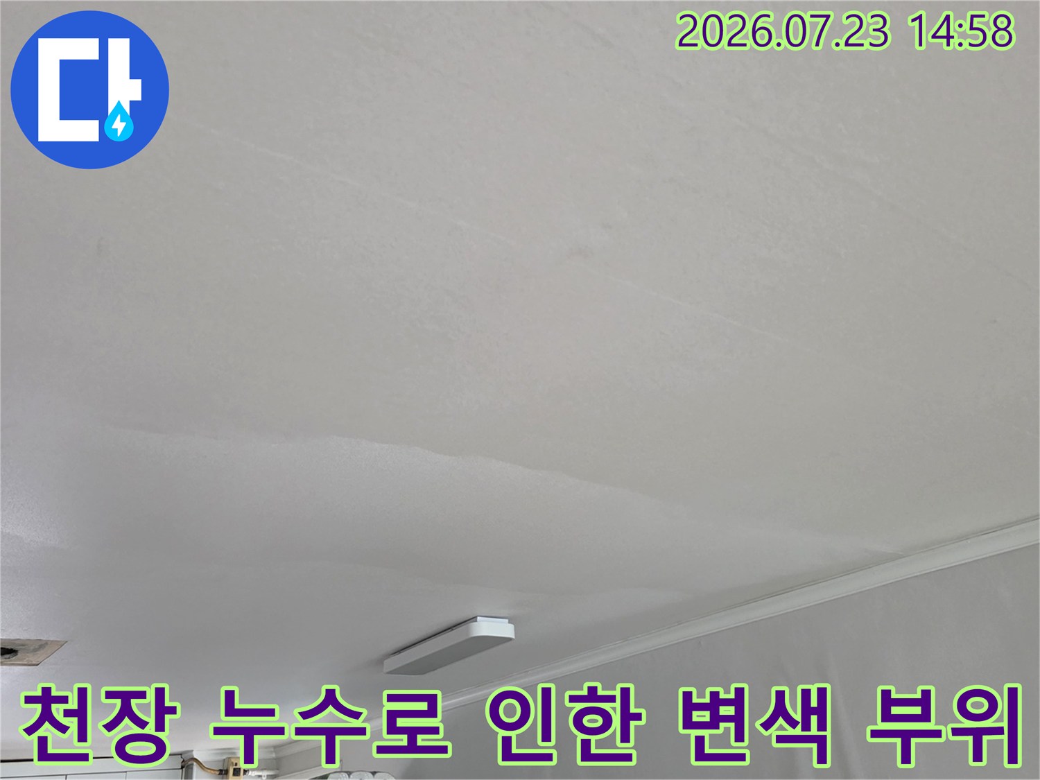 아파트 거실 천장의 흰색 도배지 위로 나타난 연한 갈색의 누수 얼룩