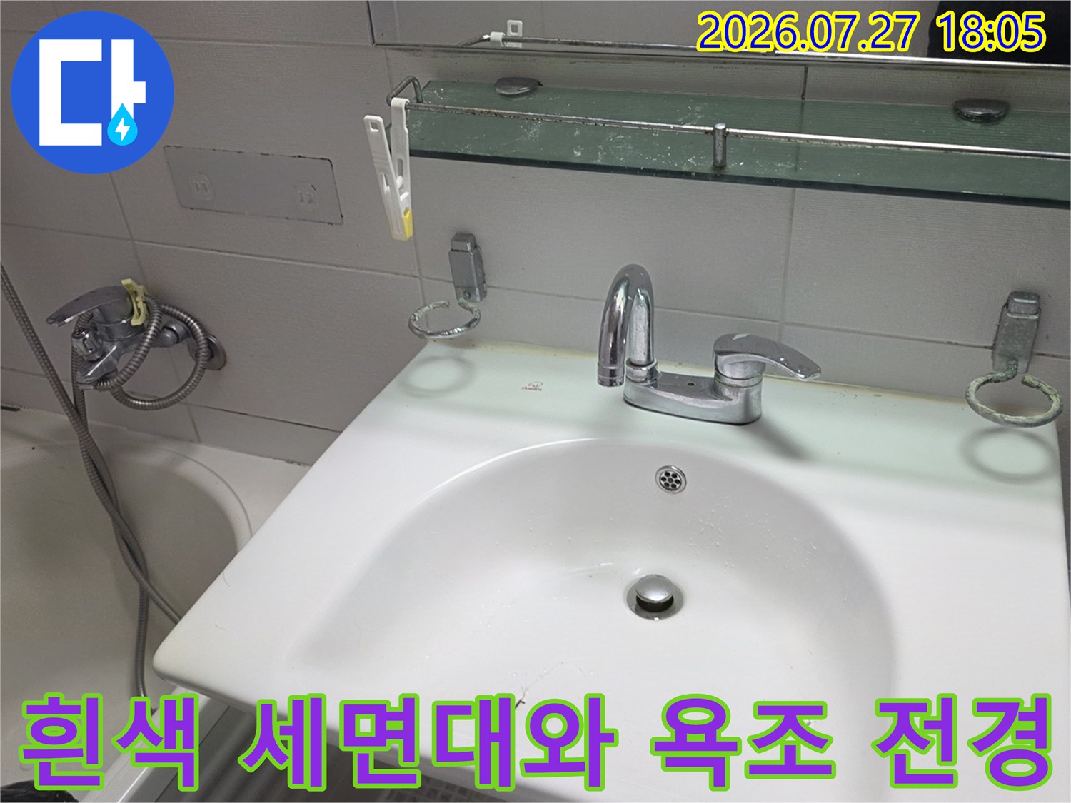 세면대 수전과 거울 선반 그리고 옆의 하얀색 욕조가 보이는 화장실-내부 모습