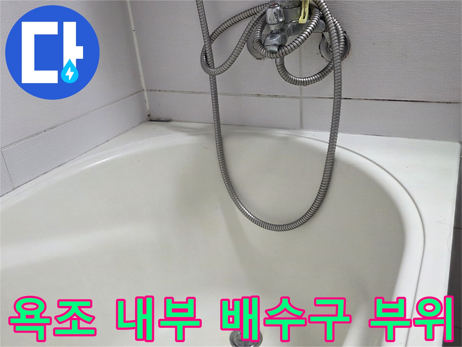 욕조 바닥에 위치한 배수구와 샤워기 호스 사진입니다.