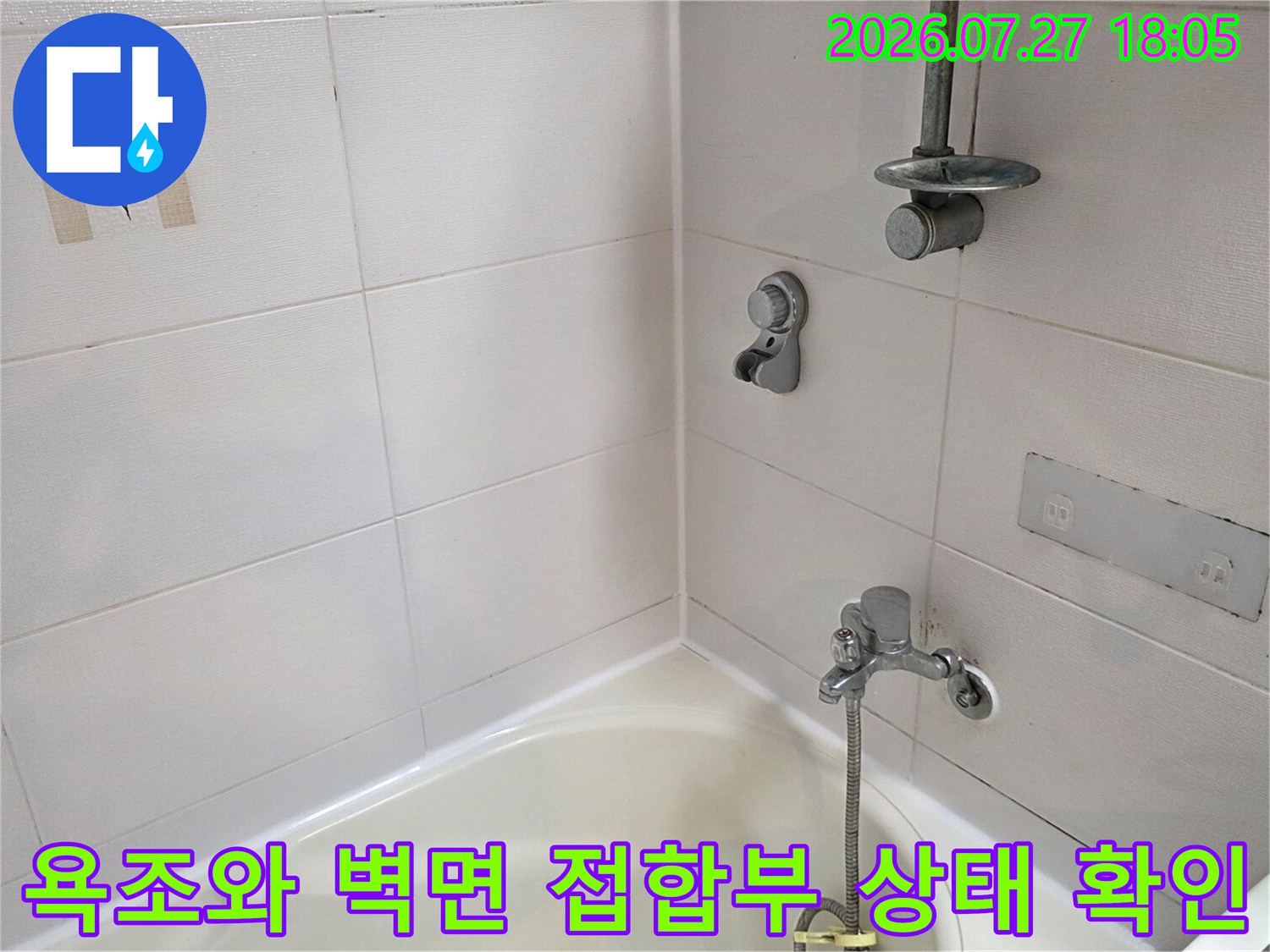 흰색 욕조 위로 설치된 샤워 수전과 벽면 타일-접합 부위를 촬영한 사진