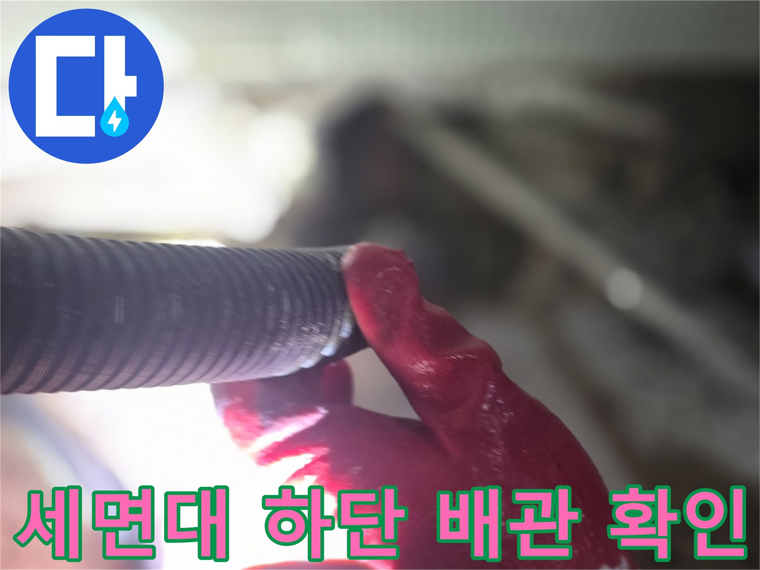 엔지니어가 손으로 세면대 아래 배관 연결 부위를 점검하는 모습