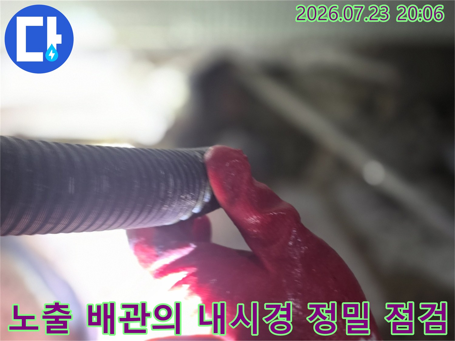 장갑을 낀 손으로 내시경 장비를 조작하며 노출된 배관 내부를 세밀하게 확인하는 모습