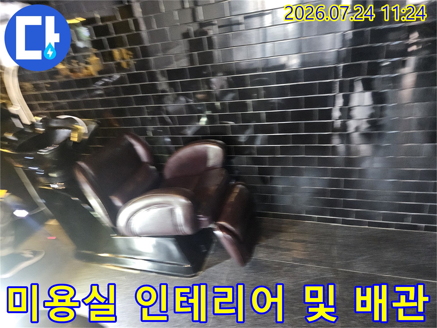 검은 타일 벽면과 샴푸대가 설치된 상업 공간
