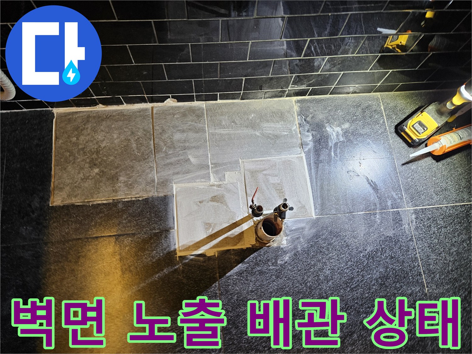 검은색 타일 벽면에 드러난 손상된 온수 배관 사진