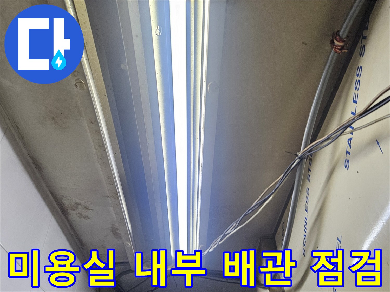 미용실 샴푸대 하부-스테인리스 선반 뒤쪽의 복잡한 전선과 배관 상태를 확인하는 모습입니다.