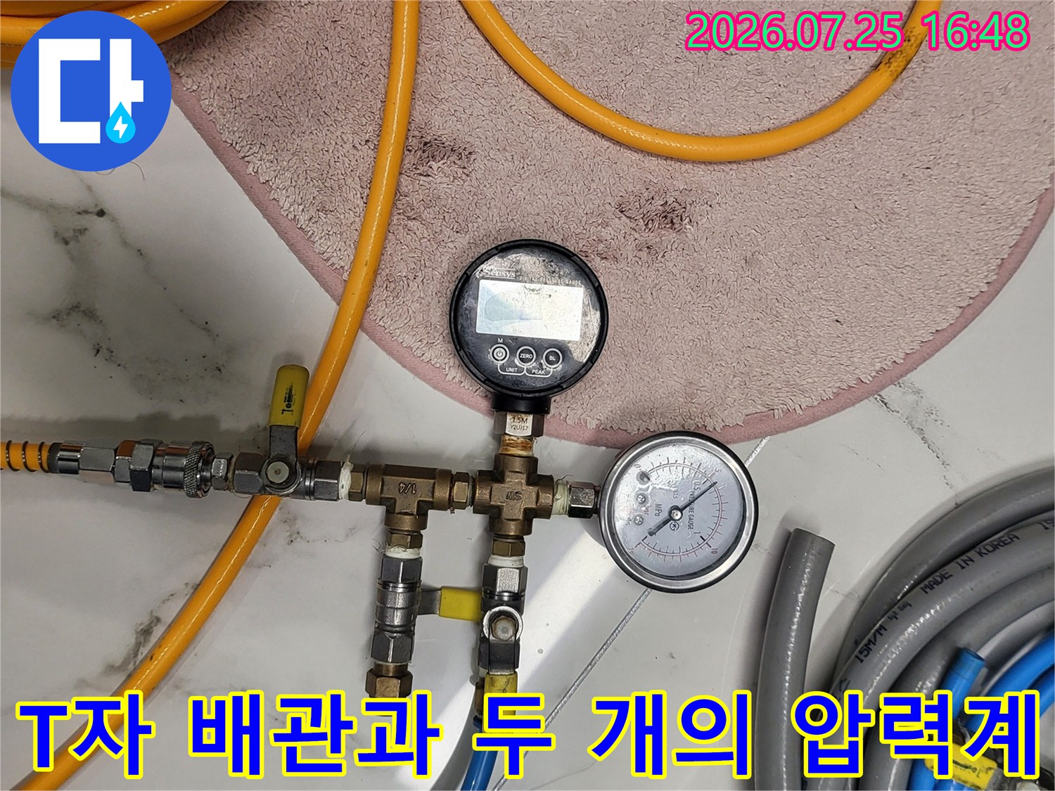 분기된 수도 배관에 연결된 투명한 게이지와 노란색 호스