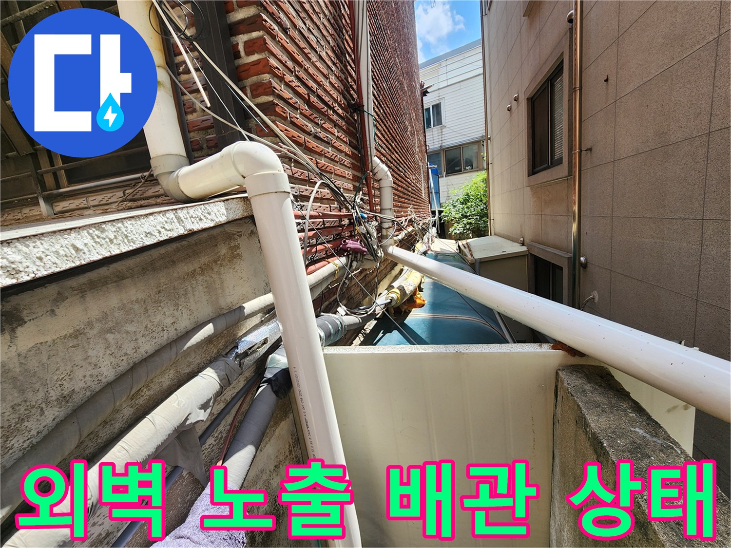 성북구 외벽에 설치된 하얀색 수도 배관과 붉은 벽돌 벽면 모습