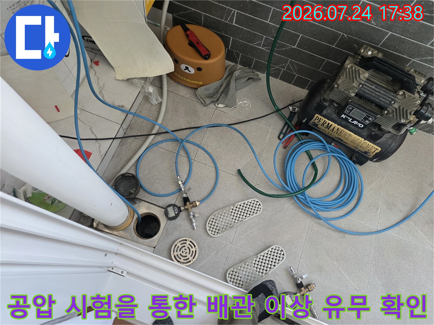콤프레샤 장비와 파란색 에어 호스를 연결하여 배관 내 압력을 체크하는 모습