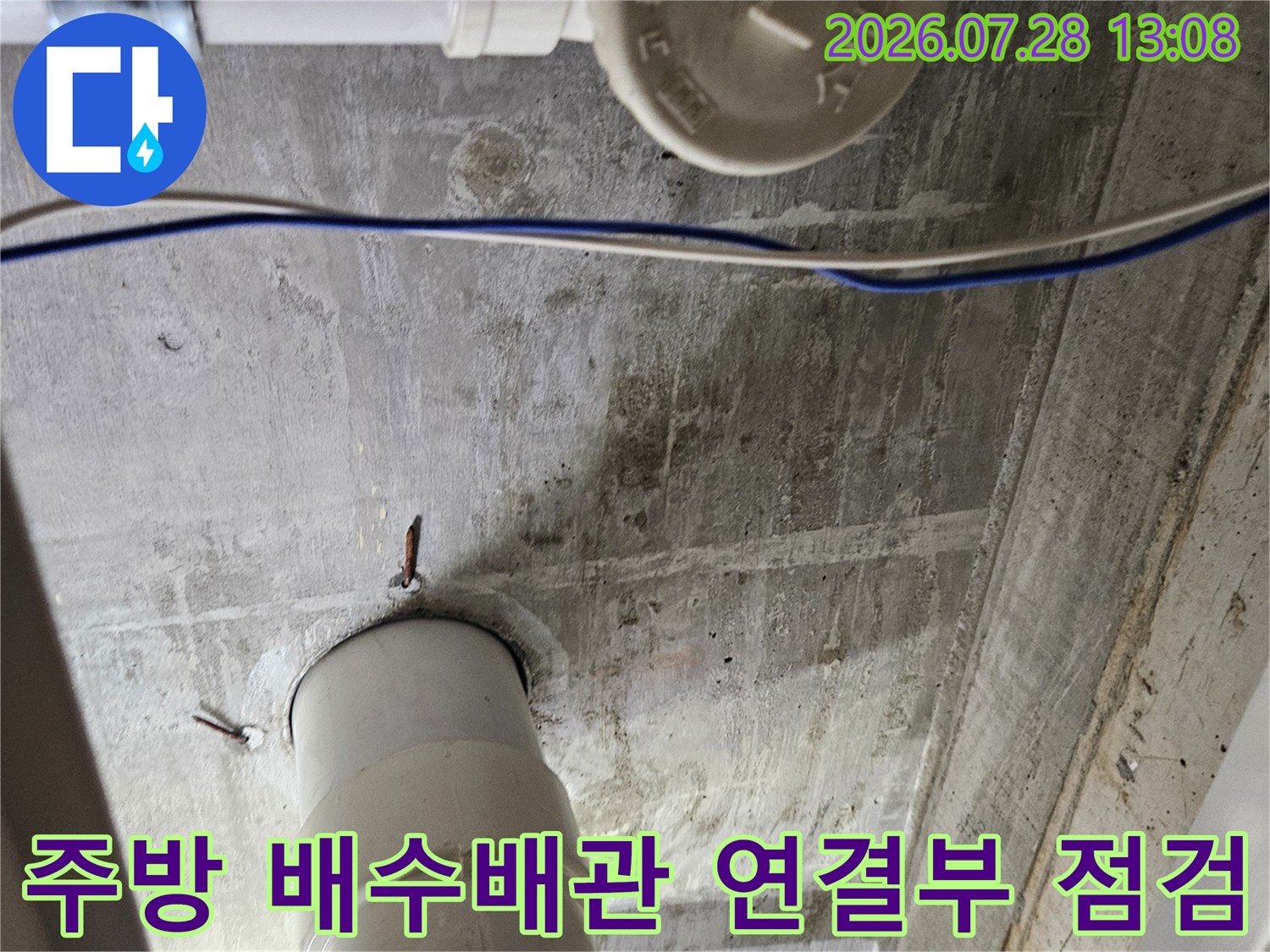 싱크대 하부 배수 배관의 접합 부위와 노출된 관을 정밀하게 점검하는 모습