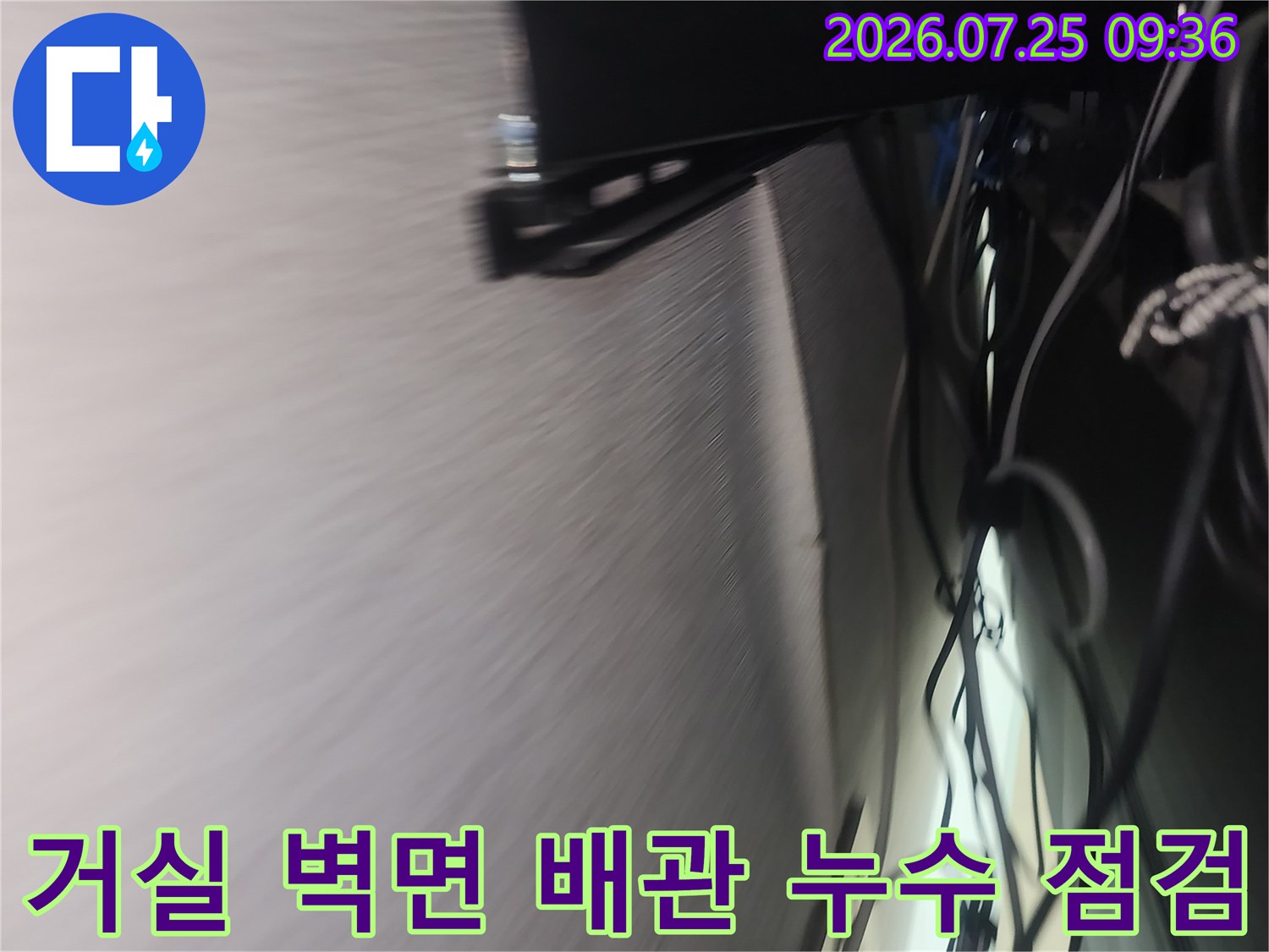거실 벽면에 노출된 복잡한 배관들과 내부로 이어지는 배관 연결부 확인 장면