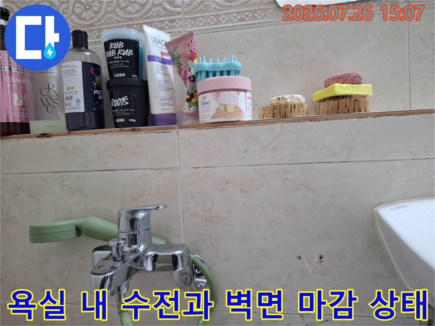 욕실 선반 위에 놓인 다양한 욕실 제품들과 그 아래 설치된 수도꼭지-누수 점검 중