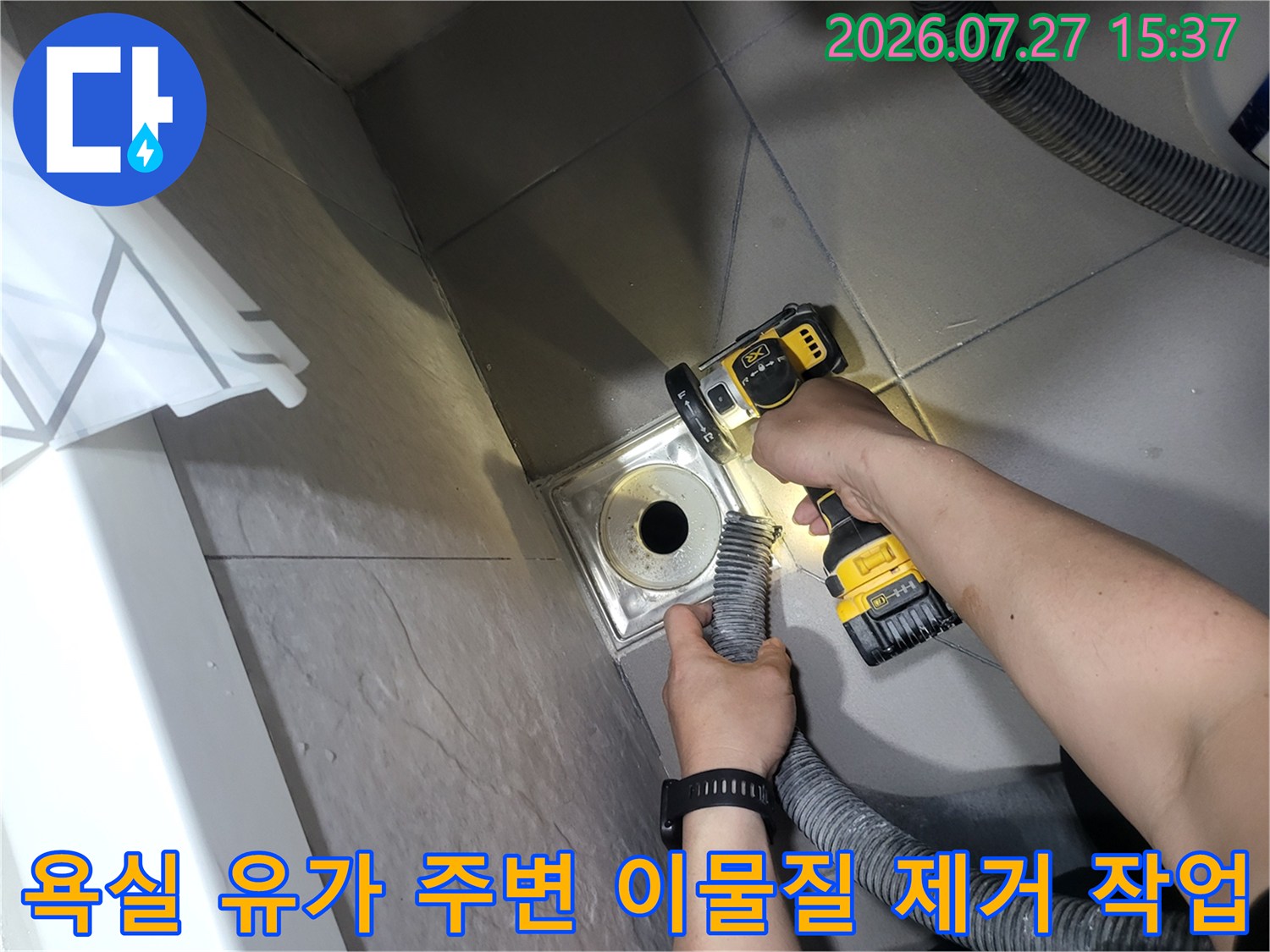 전동 브러쉬 장비를 사용하여-화장실 바닥의 배수구 주변을 깨끗하게 세척하는 모습