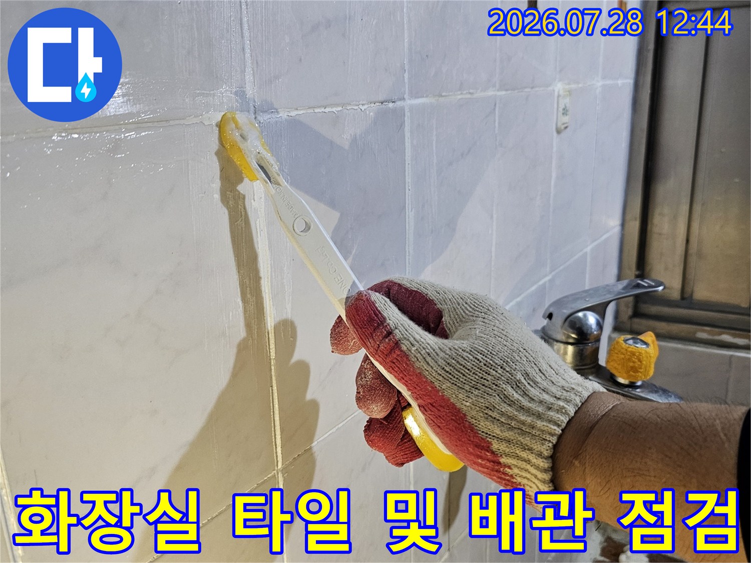 작업자가 장갑을 착용하고 화장실 바닥에서 전문 도구로 누수 지점을 파악하는 모습