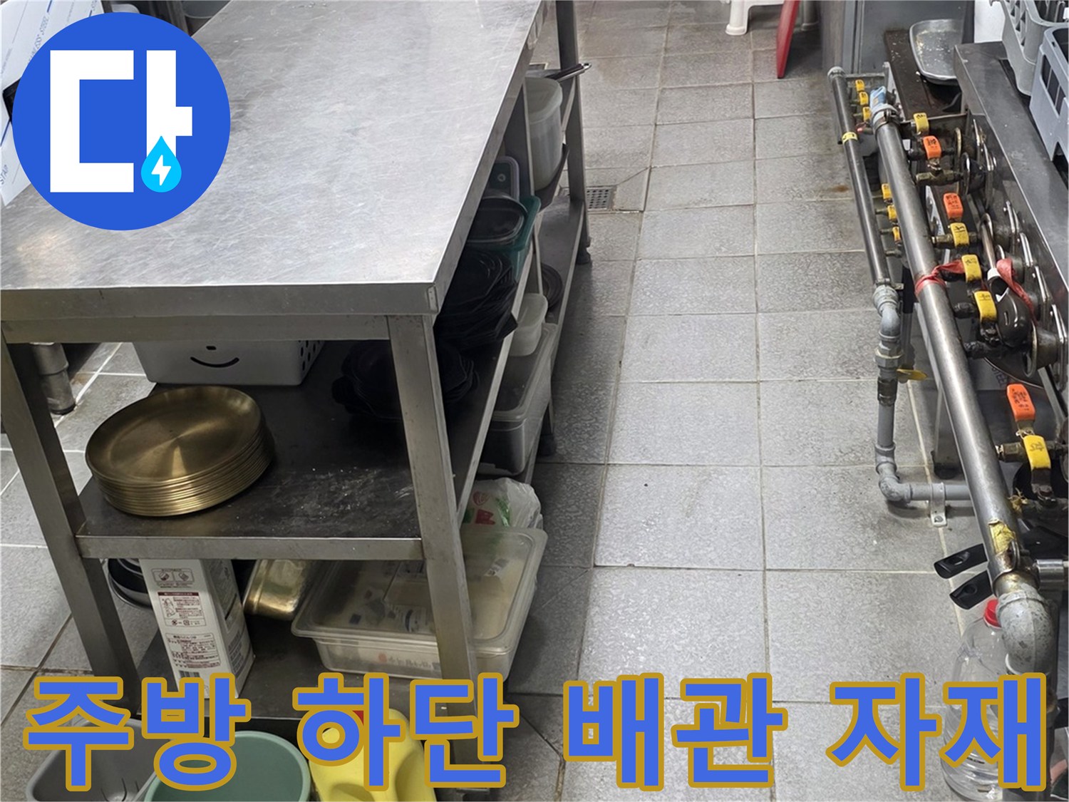 스테인리스 작업대 아래에 놓인 배관 수리용 부품과 용기들