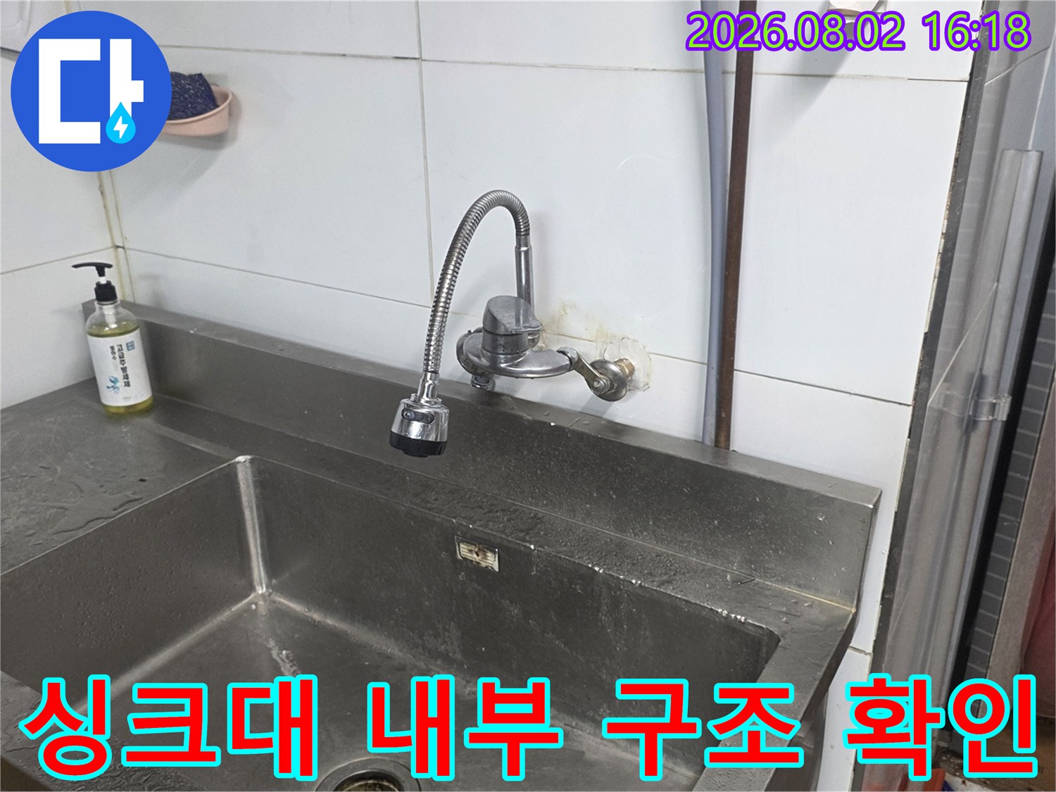 싱크대 내벽에 고정된 배관 시스템과 주변 환경을 점검하는 장면