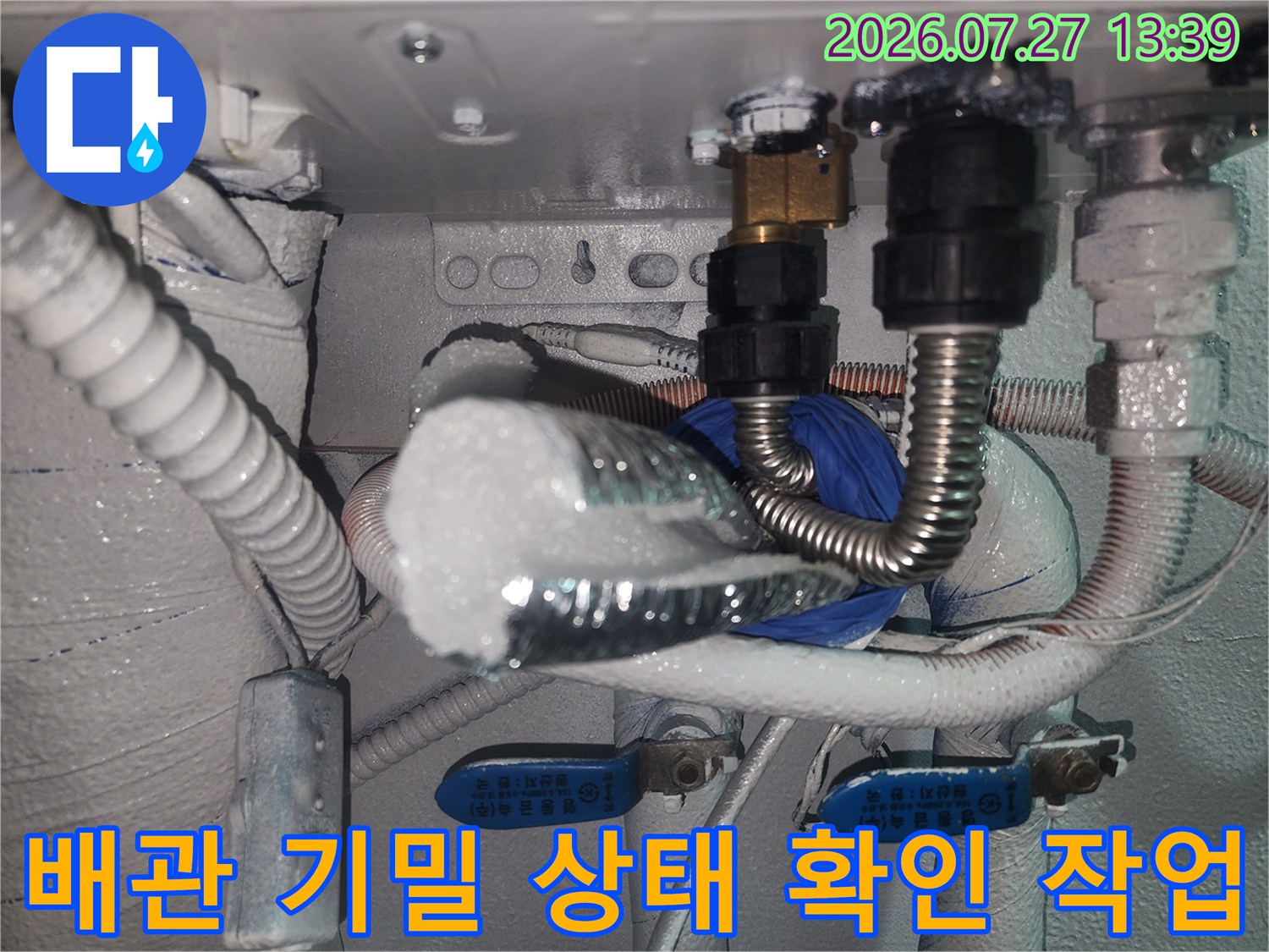 은색 주름관과 보온재가 감싸진 배관에 누수 탐지 장비를 연결한 사진