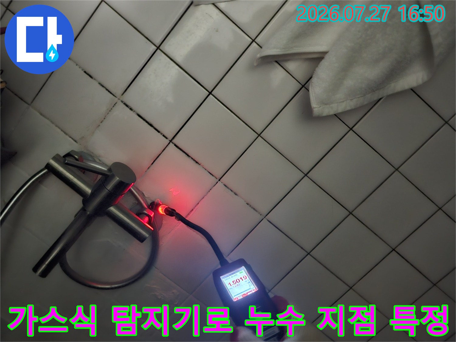 화장실 천장의 배관 연결 부위에 가스 탐지기를 사용하여 누수 여부를 정밀 측정하는 장면