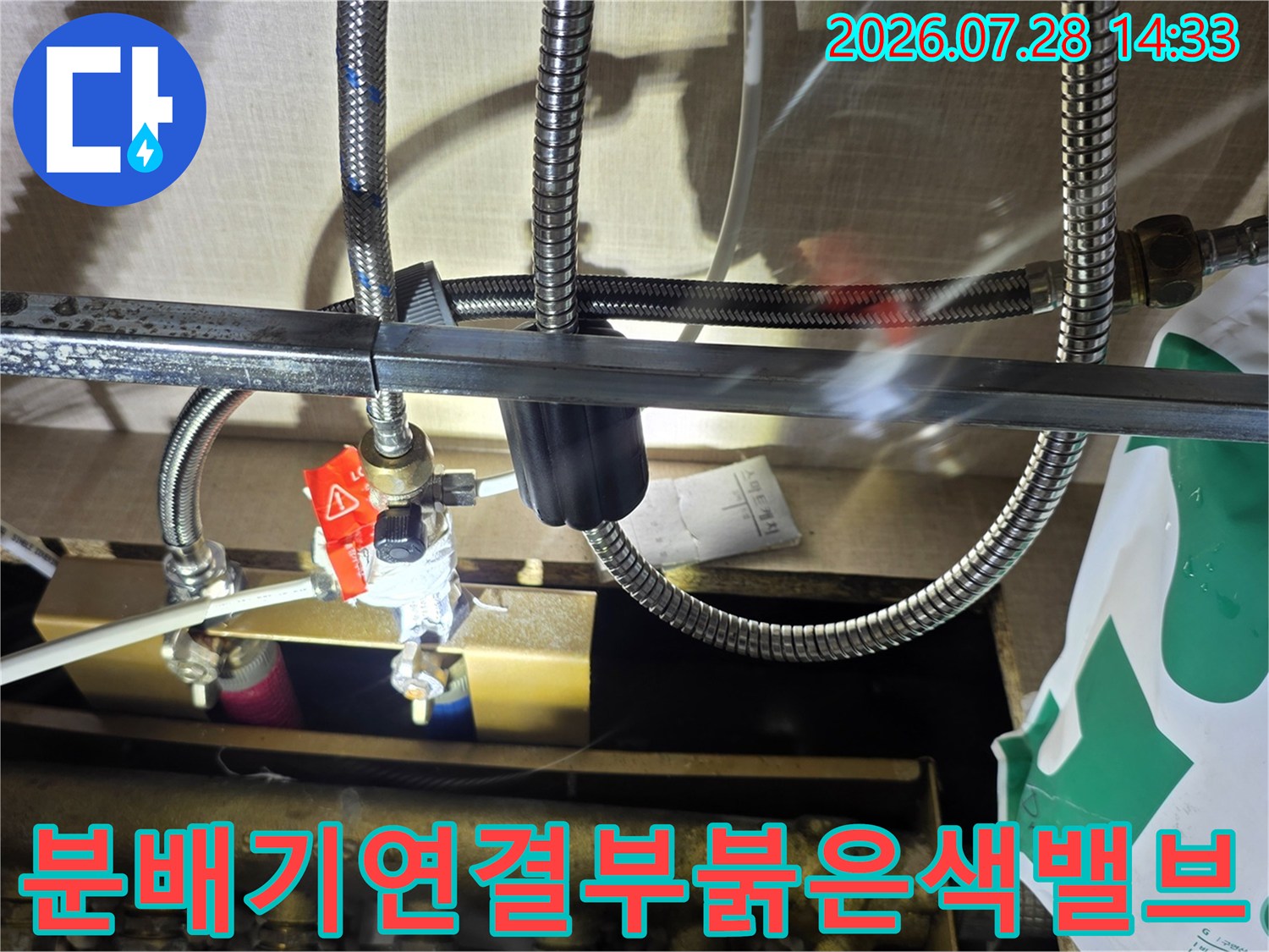 금속제 배관 분배기에 연결된 붉은색 조절 밸브와 은색 주름관-배관 시스템