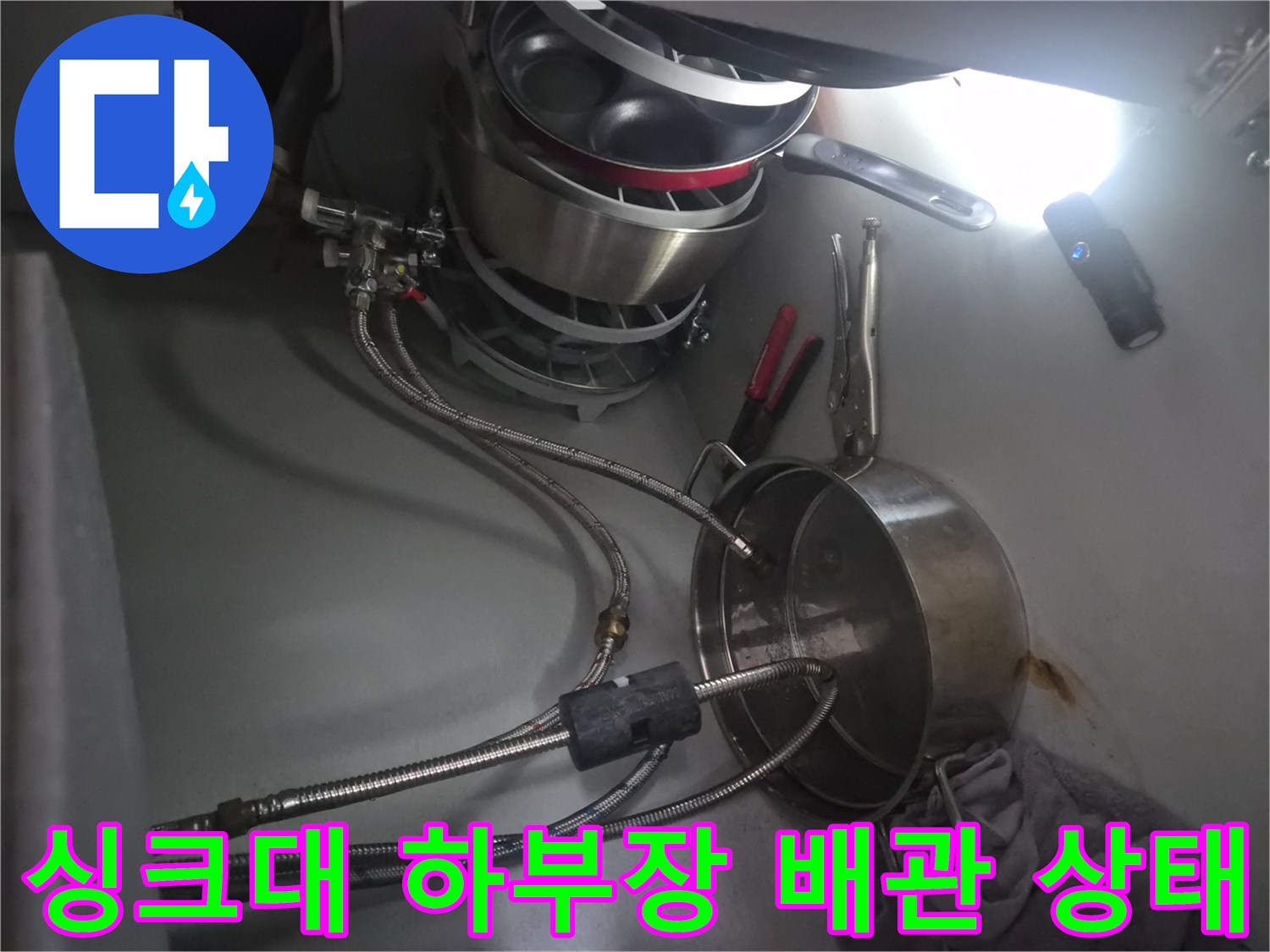 식기세척기와 싱크대 수전이 연결된-하부장 내부의 배관 모습입니다.