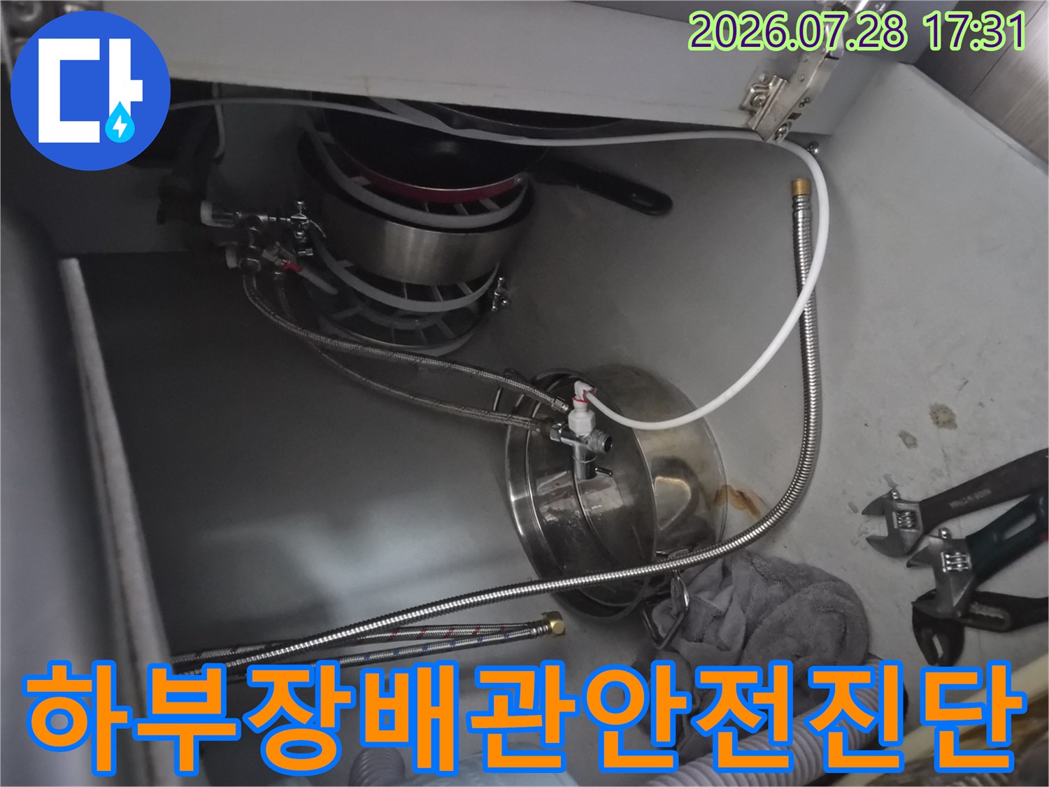 싱크대 하부에서 식기세척기 연결용 배관들의 상태를 종합적으로 점검하는 장면
