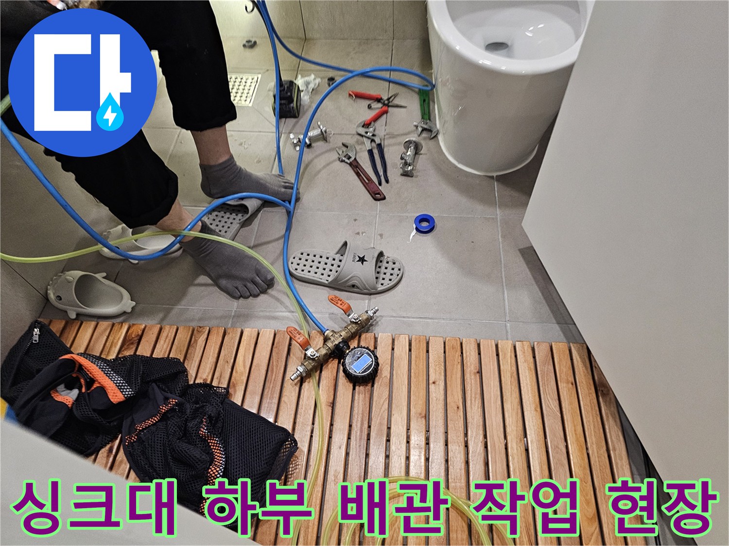 싱크대 밑 바닥에 놓인 배관 수리용 공구와 장비들