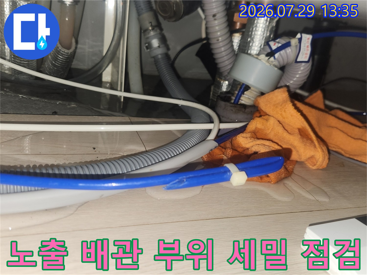 회색 주름관과 파란색 호스가 겹쳐 있는 싱크대 아래 모습