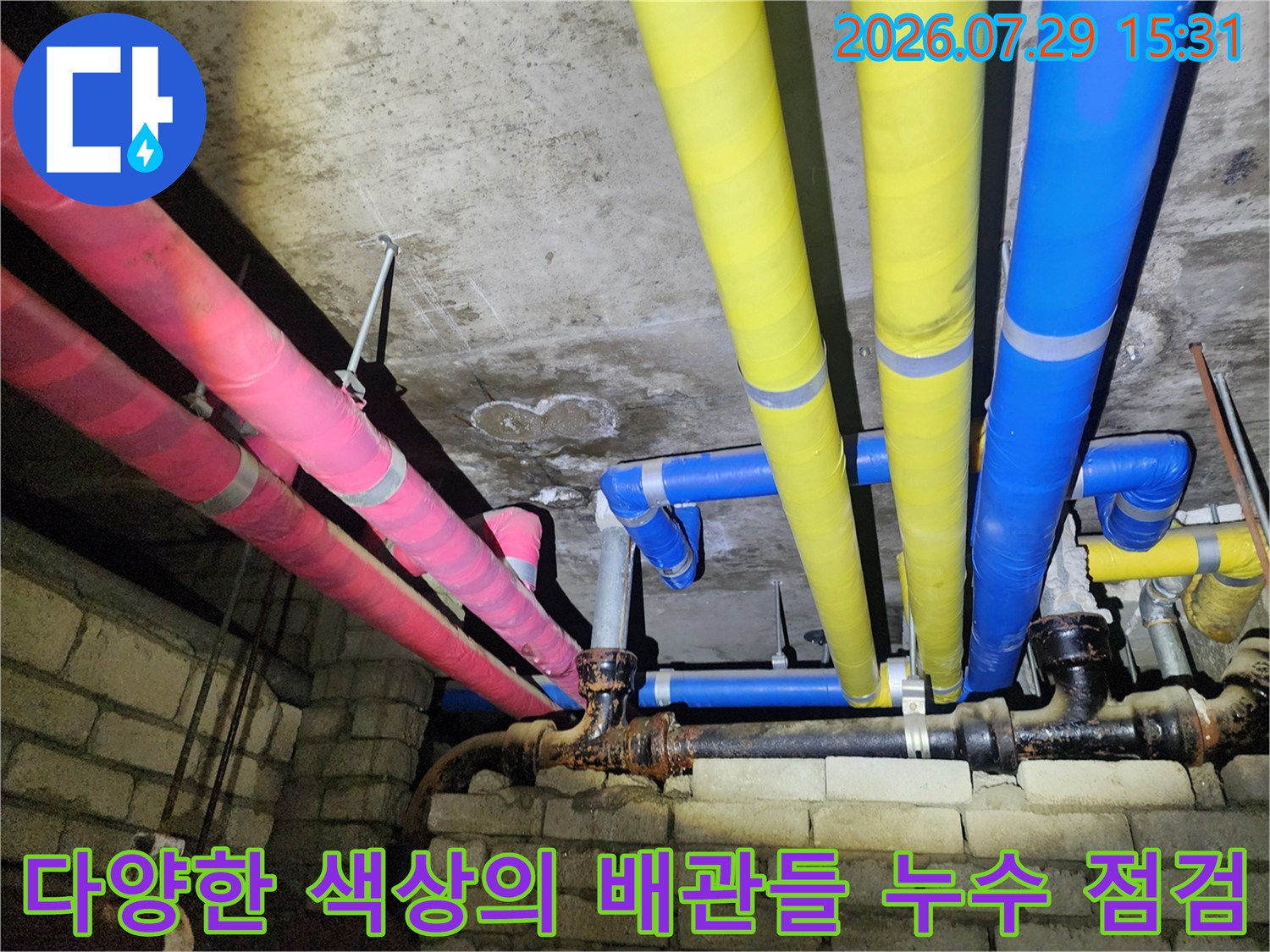 노란색과 분홍색 그리고 파란색 보온재가 씌워진 배관들이 천장에 배치된 모습