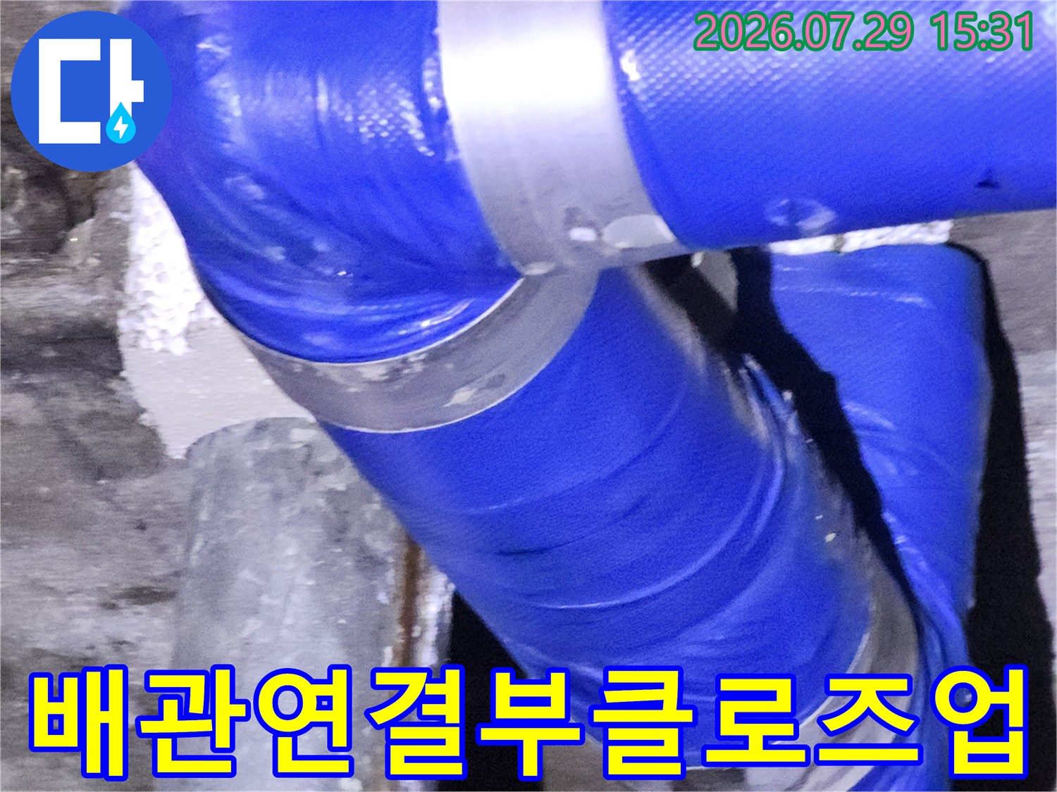파란색 보온재와 고정 클램프가 있는 배관 연결부를 확대 촬영한 사진