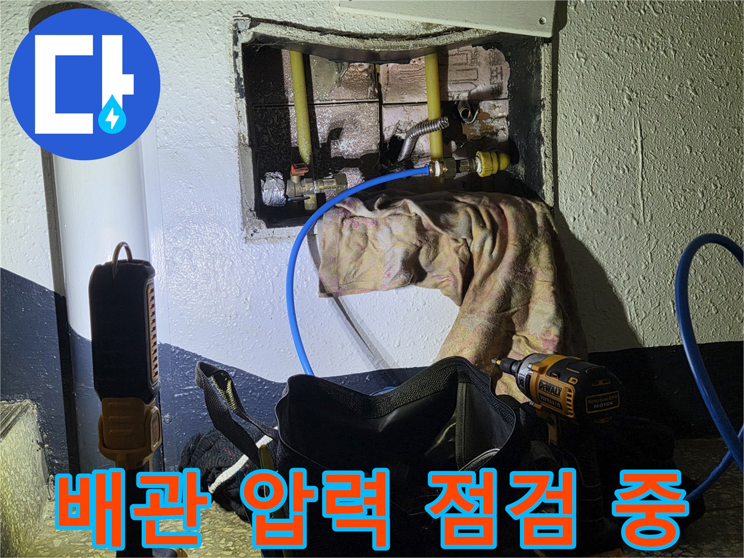 벽체 내부 배관에 파란색 호스를 연결하여 공압 테스트를 진행하는 모습