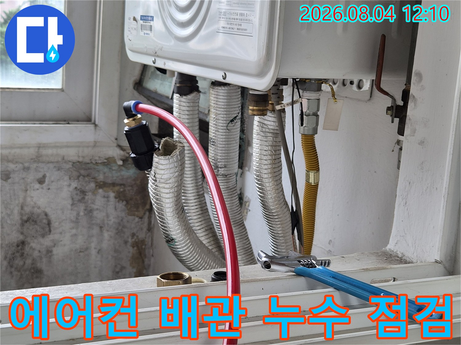 에어컨과 연결된 은색 보온재 배관을 렌치로 점검하는 모습