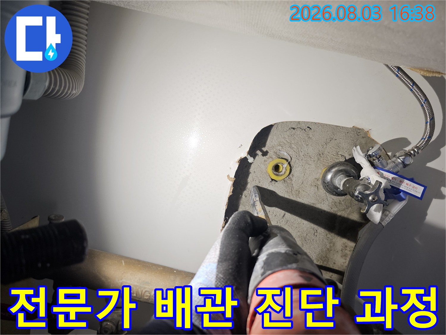 어두운 싱크대 하부에서 배관의 연결 상태를 꼼꼼하게 점검하는 장면