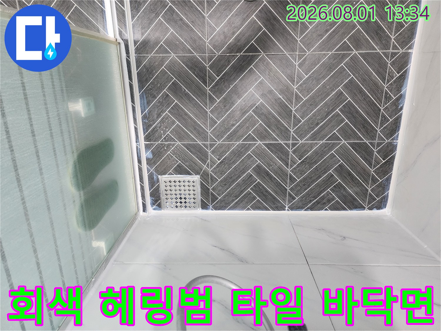 고급스러운 회색 계열의 헤링범 패턴 타일과 사각형 배수구 시설