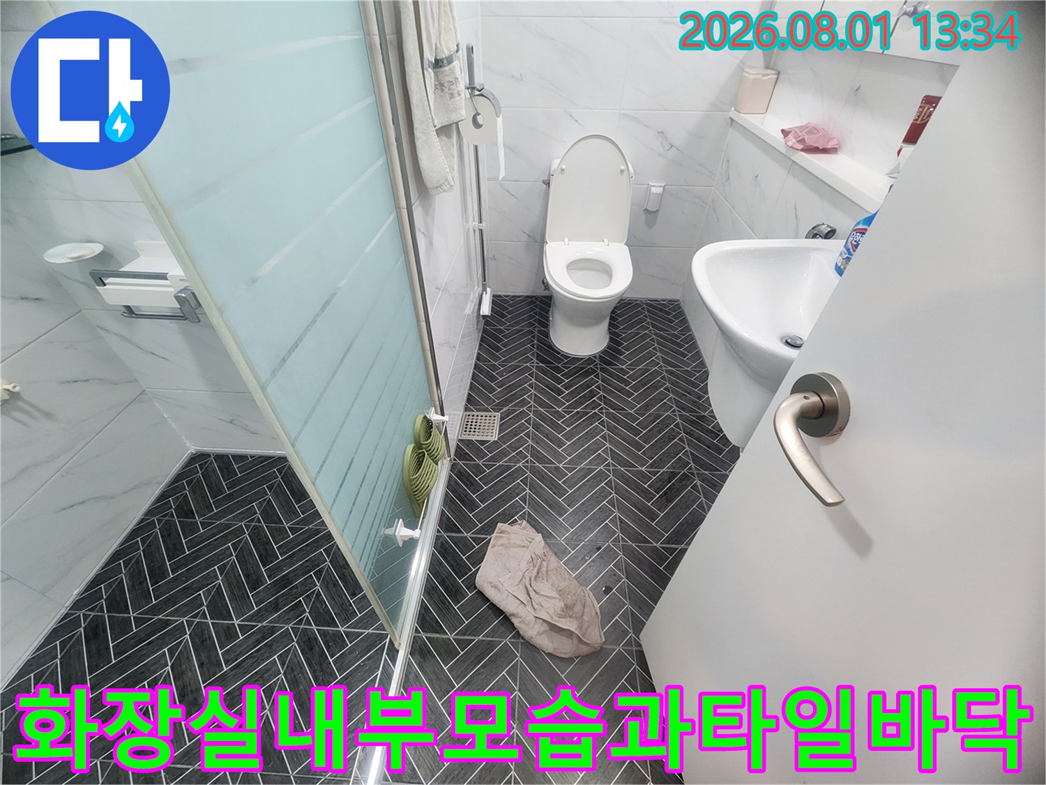 헤링본 패턴의 어두운색 타일로 마감된 세련된 화장실 내부 전경