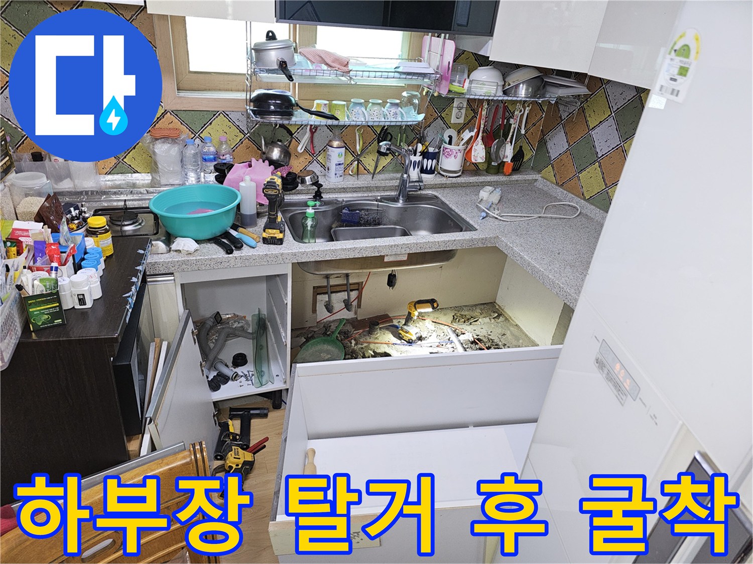 싱크대 밑바닥을 파내어 누수가 진행 중인 배관 부위를 노출시킨 현장 사진입니다.