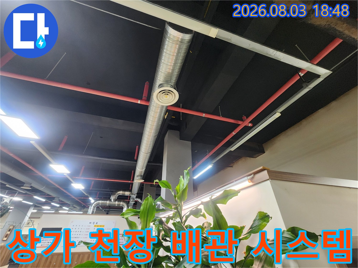복잡한 구조의 상부 배관과 조명 시설이 배치된 공간