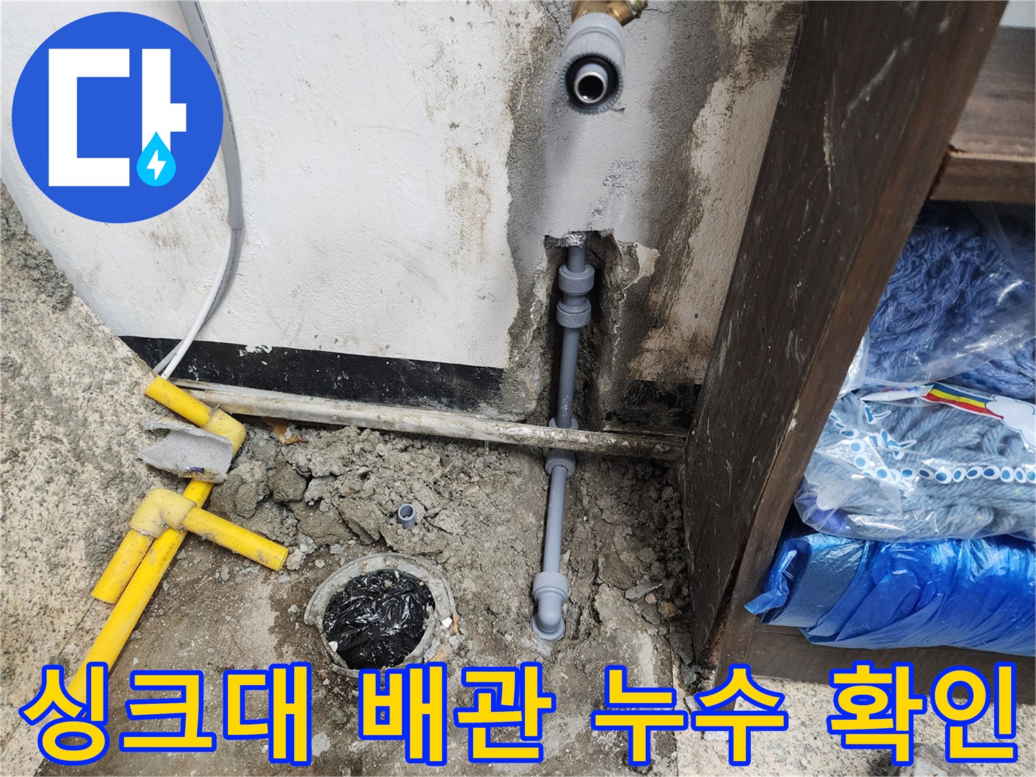 싱크대 아래 벽면 배관의 연결 부위와 물이 스며 나온 흔적 사진