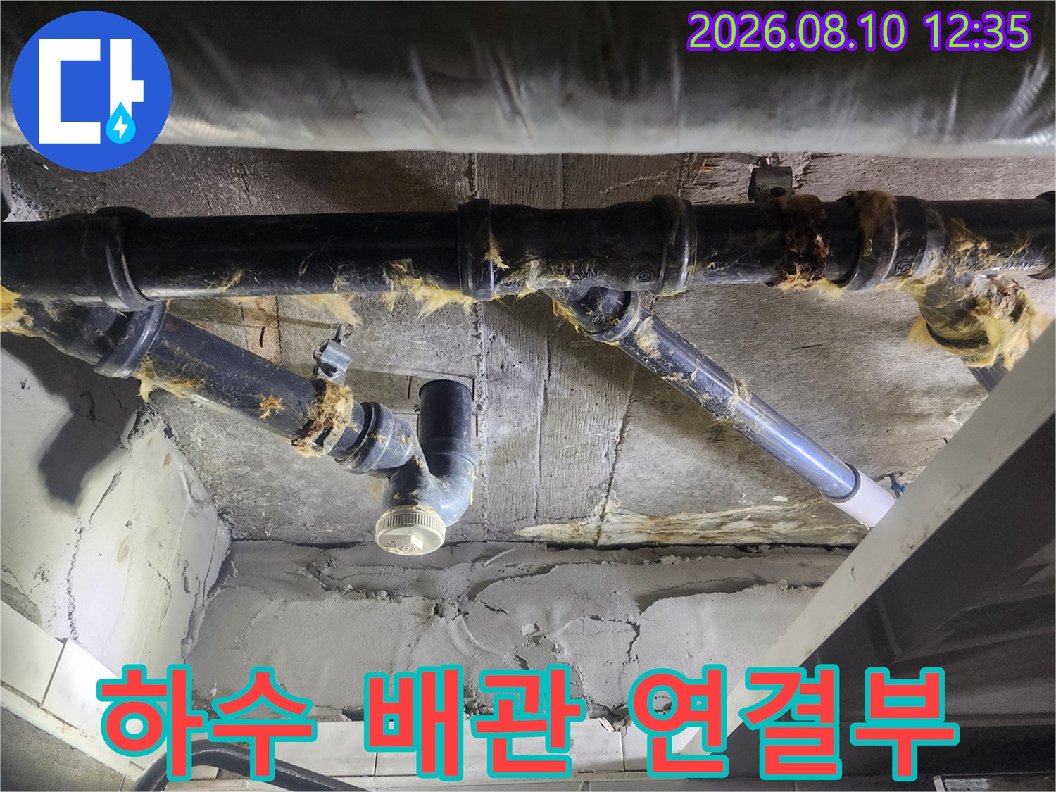 낡은 테이핑과 보온재로 감겨 있는 하수 배관의 연결 부위 상세 사진입니다.