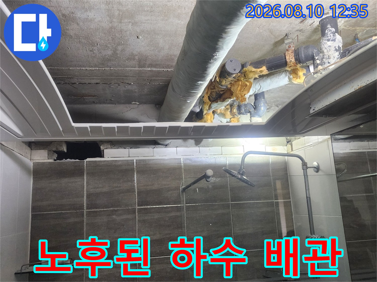 욕실 천장 내부의 낡은 하수 배관과 손상된 보온재를 보여주는 사진입니다.