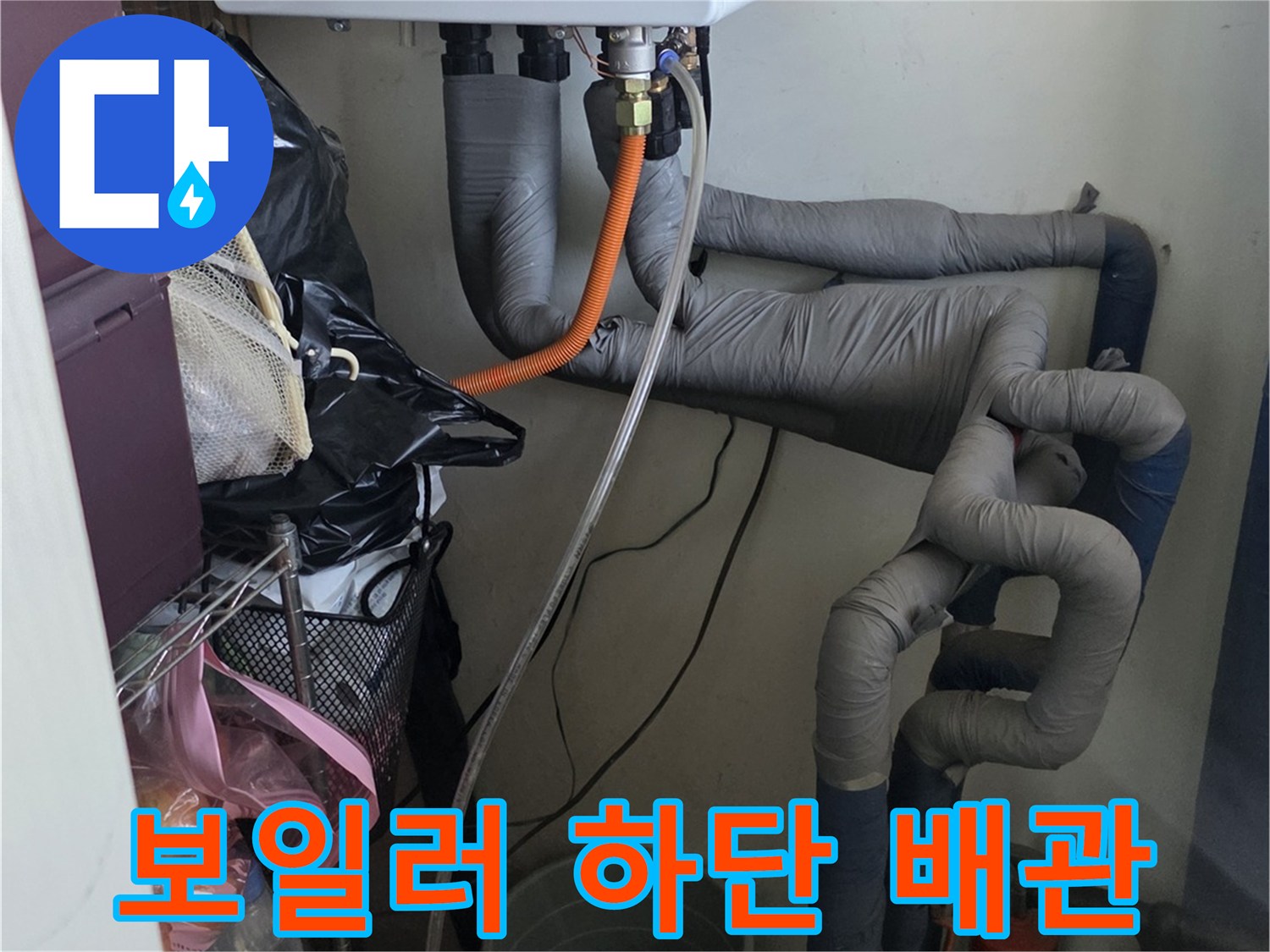 회색 보온재로 감싸진 배관과 주황색 유연 호스의 연결 부위 상세 사진