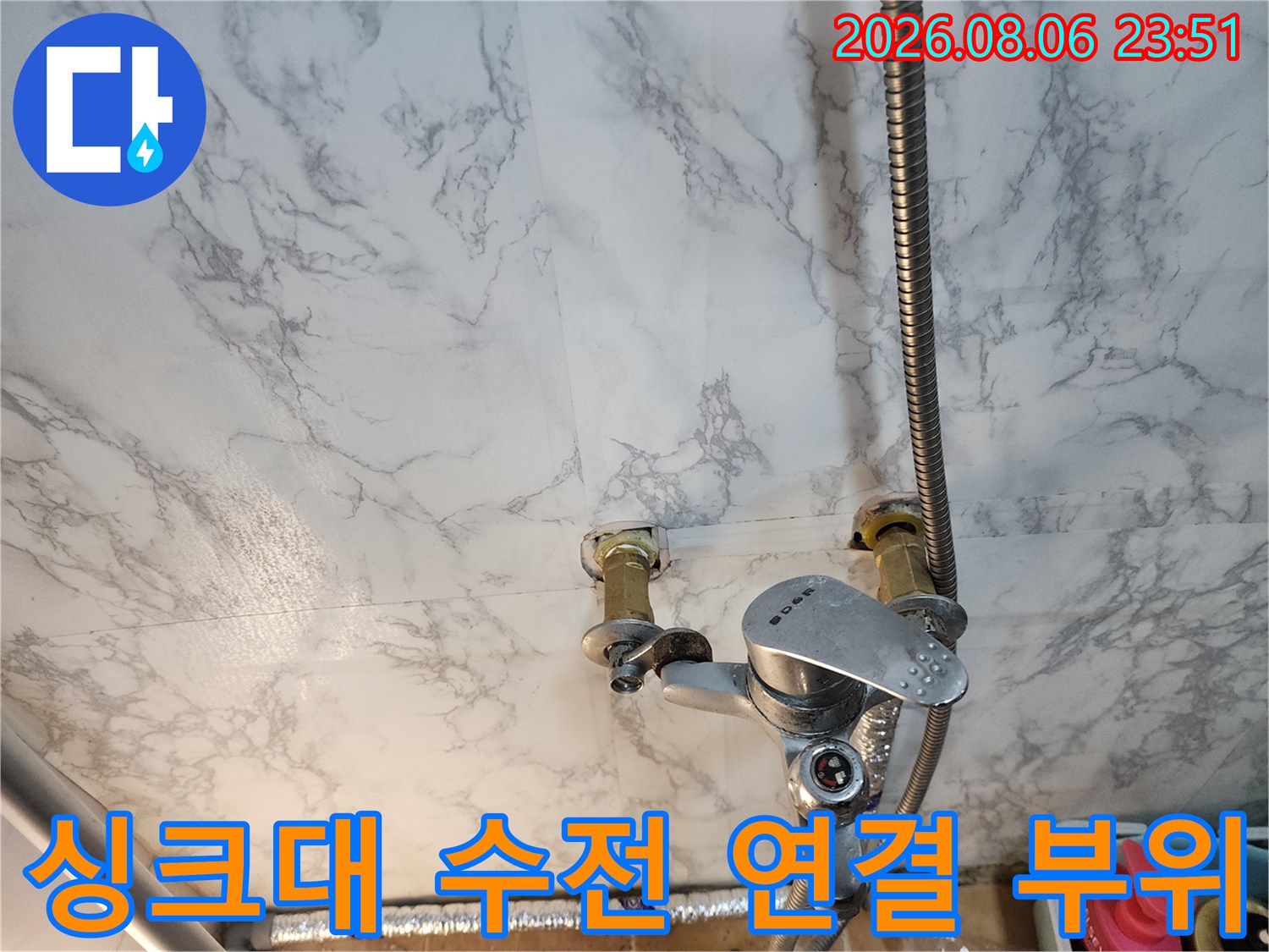 벽면 마감재와 연결된 금속제 수전 및 배관의 근접 사진입니다.