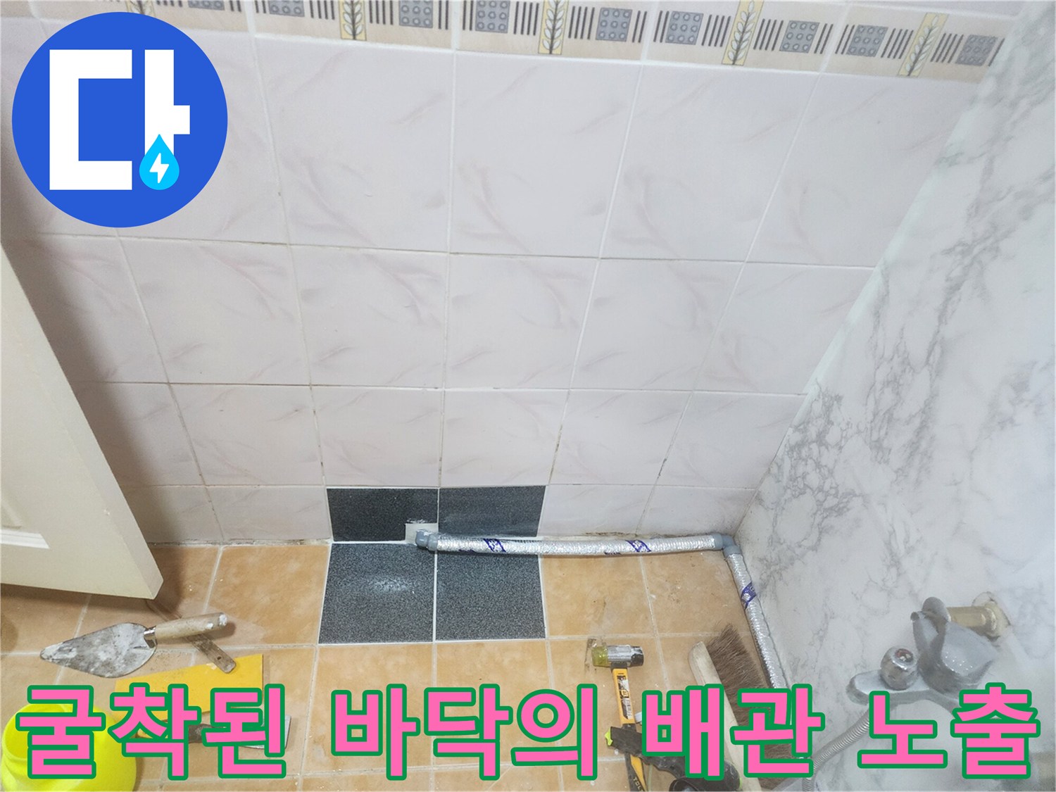 타일을 제거하여 드러난 배관과 주변 미장 작업 도구들