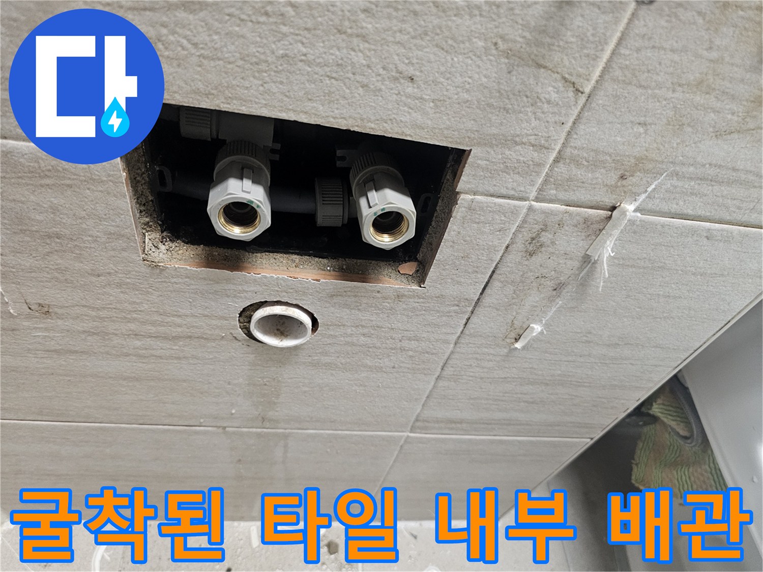 타일 사이 틈으로 보이는 노출된 수전 연결용 부속품들