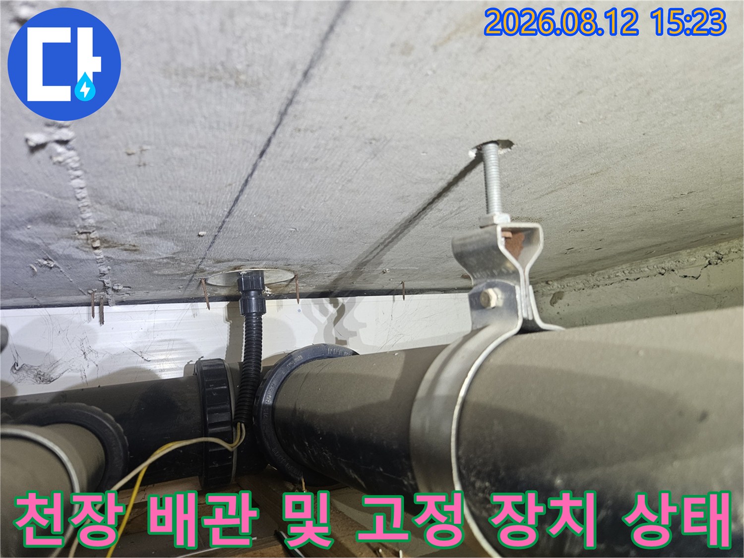 전산볼트로 천장에 고정된 검은색 하수 배관과 금속 행거-측면 사진