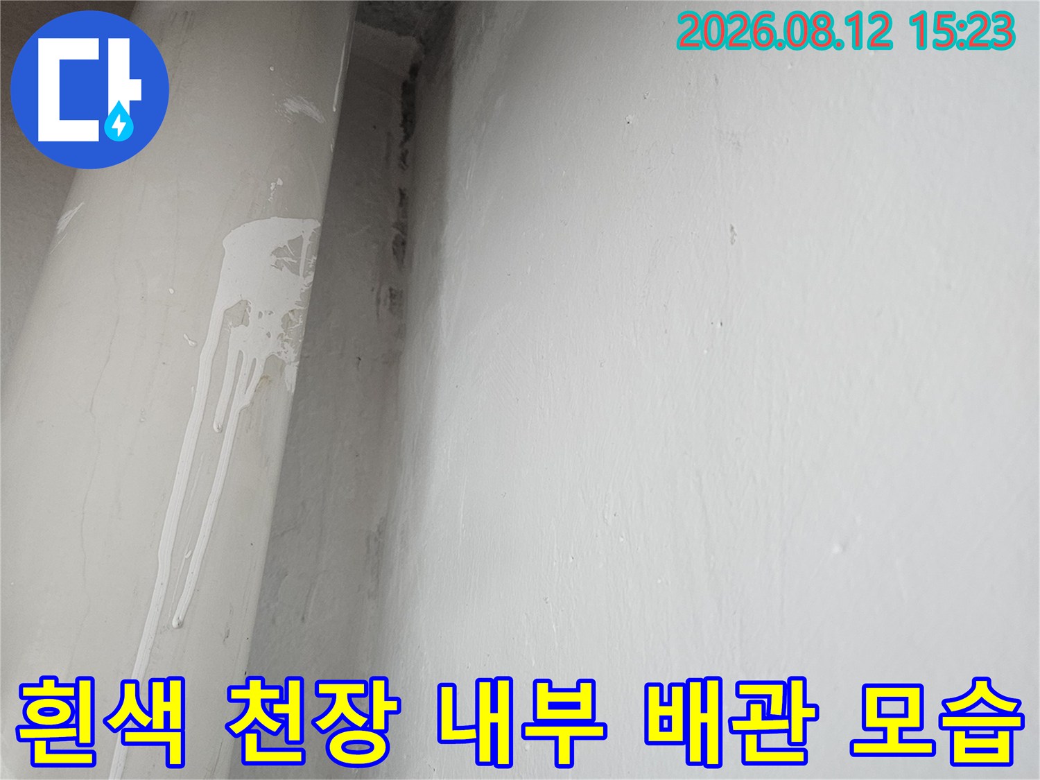 천장 구석에 위치한 회색 PVC 배관과 마감재의 접합 부분 사진