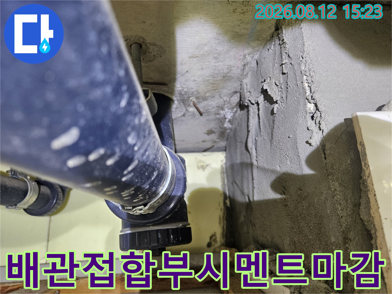 파란색 배수관이-거칠게 마감된 시멘트 벽체에 고정되어 있는 모습